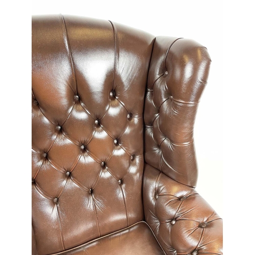 169 - WING ARMCHAIR, deep buttoned brown leather, with brass stud work and stretchered legs with buttoned ... 