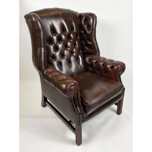 169 - WING ARMCHAIR, deep buttoned brown leather, with brass stud work and stretchered legs with buttoned ... 