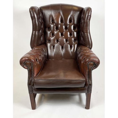 169 - WING ARMCHAIR, deep buttoned brown leather, with brass stud work and stretchered legs with buttoned ... 