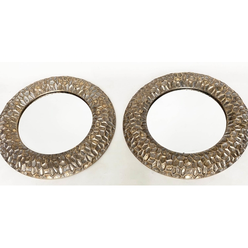 291 - CIRCULAR WALL MIRRORS, a pair, with 'hammered' cushion gilt metal frames, 73cm W. (2)