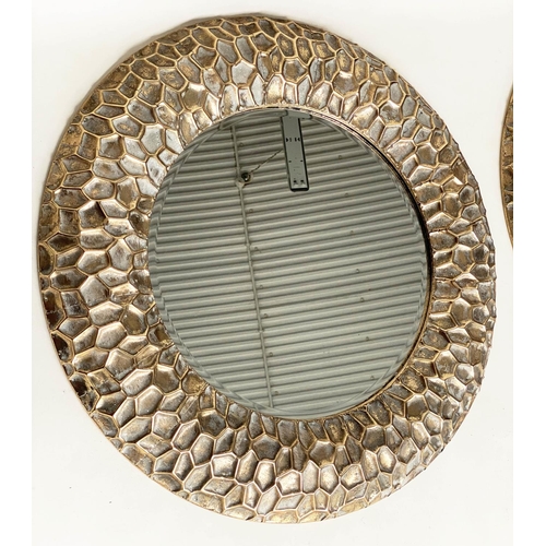 291 - CIRCULAR WALL MIRRORS, a pair, with 'hammered' cushion gilt metal frames, 73cm W. (2)