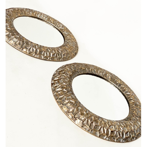 291 - CIRCULAR WALL MIRRORS, a pair, with 'hammered' cushion gilt metal frames, 73cm W. (2)