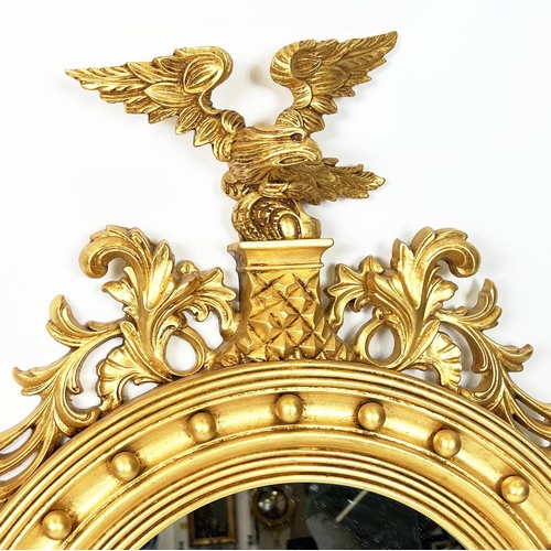 160 - WALL MIRRORS, a pair, Regency design, gilt circular frames with an eagle surmount, 90cm x 56cm. (2)