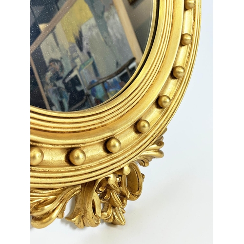 160 - WALL MIRRORS, a pair, Regency design, gilt circular frames with an eagle surmount, 90cm x 56cm. (2)