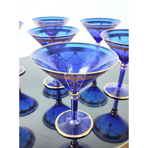 30 - A SET OF VENETIAN COBALT BLUE AND GOLD HAND PAINTED GLASSES, seven champagne coupes, nine martini gl... 