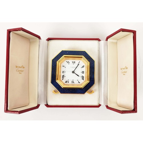 65 - A CARTIER TRAVELLING CLOCK, simulated lapis lazuli enameled gilt octagonal case, white dial with Rom... 