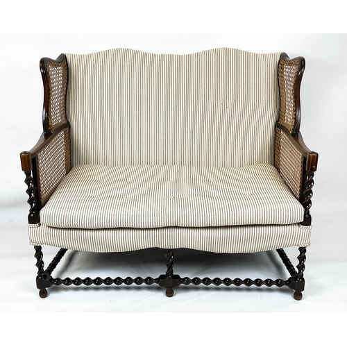 199 - BERGERE WING SOFA, 99cm H x 117cm W, circa 1920, walnut, with  caned arms and ticking upholstery.