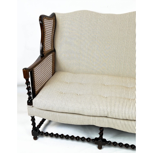 199 - BERGERE WING SOFA, 99cm H x 117cm W, circa 1920, walnut, with  caned arms and ticking upholstery.