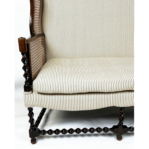 199 - BERGERE WING SOFA, 99cm H x 117cm W, circa 1920, walnut, with  caned arms and ticking upholstery.