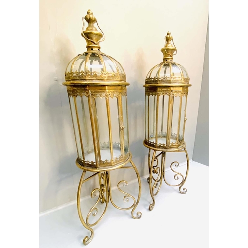 329 - STORM LANTERNS ON STANDS, 115cm H x 34cm diam., Regency style, gilt metal frames. (2)