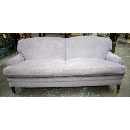 491 - HOWARD STYLE SOFA, 87cm H x 218cm W x 107cm D, in Designers Guild lilac chenille on brass castors.