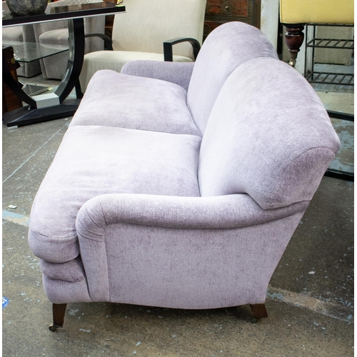 491 - HOWARD STYLE SOFA, 87cm H x 218cm W x 107cm D, in Designers Guild lilac chenille on brass castors.