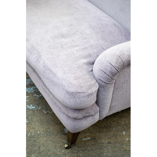 491 - HOWARD STYLE SOFA, 87cm H x 218cm W x 107cm D, in Designers Guild lilac chenille on brass castors.