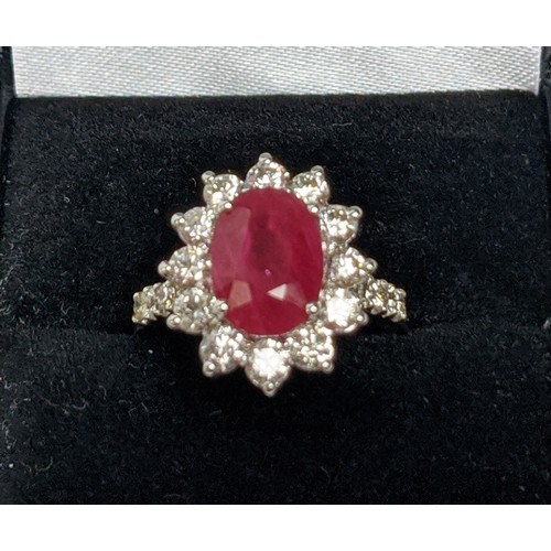 47 - AN 18CT WHITE GOLD RUBY AND DIAMOND CLUSTER RING, with diamond set shoulders, the central oval cut r... 
