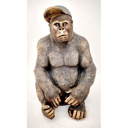 437 - GORILLA WEARING A BASEBALL CAP, 60cm H x 40cm W x 34cm D, faux bronze finished resin.