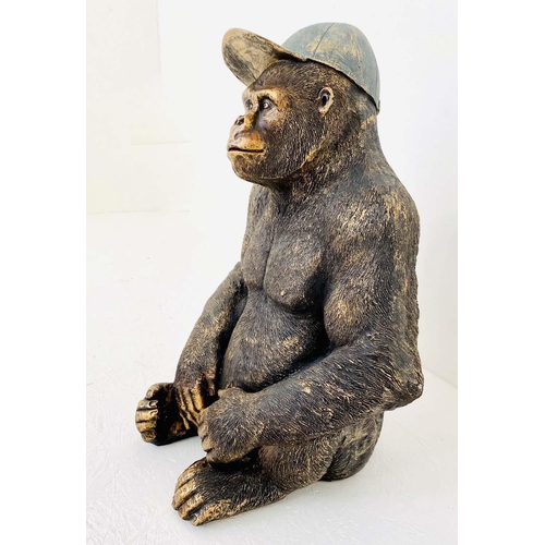 437 - GORILLA WEARING A BASEBALL CAP, 60cm H x 40cm W x 34cm D, faux bronze finished resin.