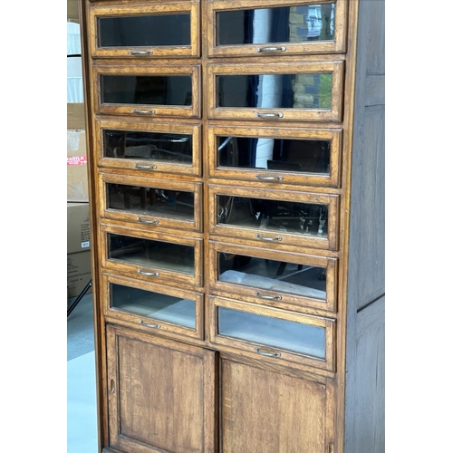 246 - HABERDASHERY CABINET BY DUDLEY & CO, mid 20th century oak with sixteen glazed drawers above two slid... 