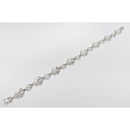 57 - A 9CT WHITE GOLD DIAMOND BRACELET, wave-form, fitted with round cut diamonds totalling 0.20 carats, ... 