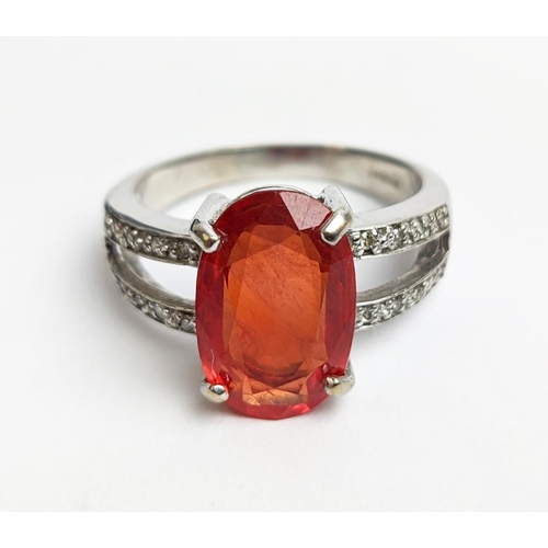 61 - AN 18CT WHITE GOLD ORANGE SAPPHIRE AND DIAMOND SET DRESS RING, the central oval stone of 3.88 carats... 