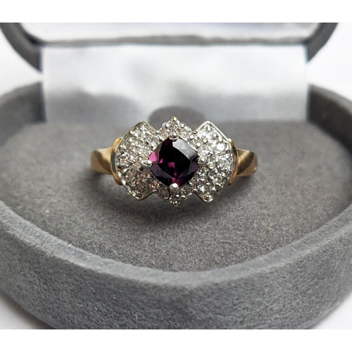 64 - A 9CT GOLD RHODOLITE GARNET SET DRESS RING, the central cushion cut stone of 0.50 carat, surrounded ... 