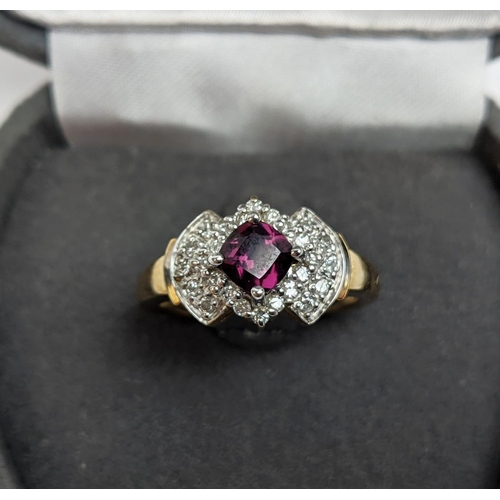 64 - A 9CT GOLD RHODOLITE GARNET SET DRESS RING, the central cushion cut stone of 0.50 carat, surrounded ... 