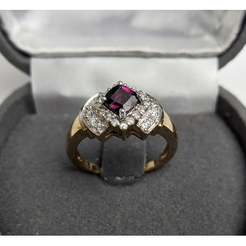 64 - A 9CT GOLD RHODOLITE GARNET SET DRESS RING, the central cushion cut stone of 0.50 carat, surrounded ... 