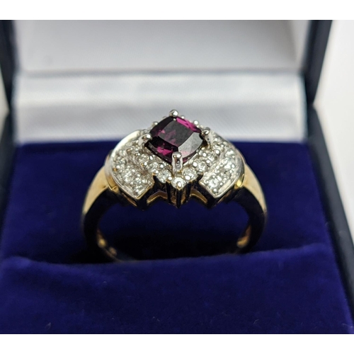 64 - A 9CT GOLD RHODOLITE GARNET SET DRESS RING, the central cushion cut stone of 0.50 carat, surrounded ... 