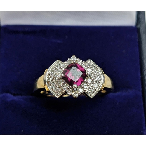 64 - A 9CT GOLD RHODOLITE GARNET SET DRESS RING, the central cushion cut stone of 0.50 carat, surrounded ... 