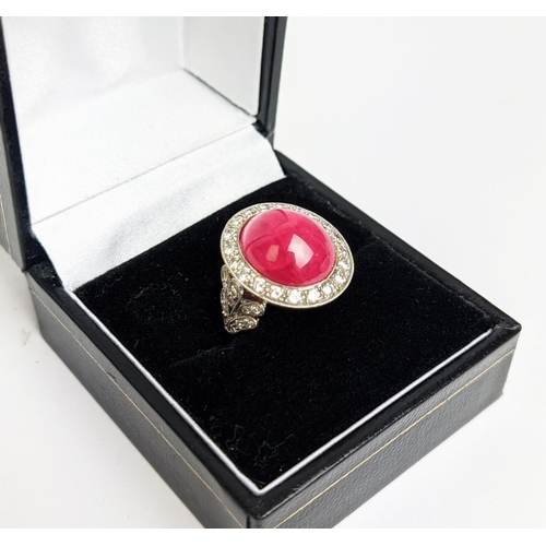 12 - RUBY AND DIAMOND DRESS RING, white metal shank, the central ruby cabochon of approx 10 carats, size ... 