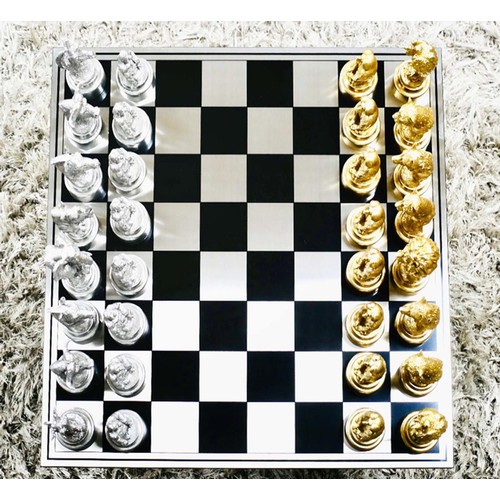 657 - CHESS SET, chequered board complete with silvered and gilt finish animal form pieces, 60cm x 60cm.