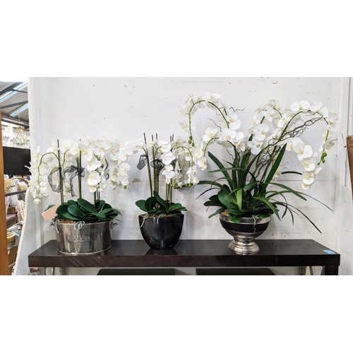 397 - FAUX ORCHID DISPLAYS, a collection of three, differing sizes and in differing vessels, 110cm at tall... 