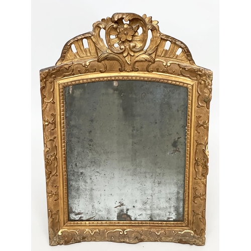 241 - WALL MIRROR, late 18th century French carved giltwood and gesso with foliate crest and distressed ea... 