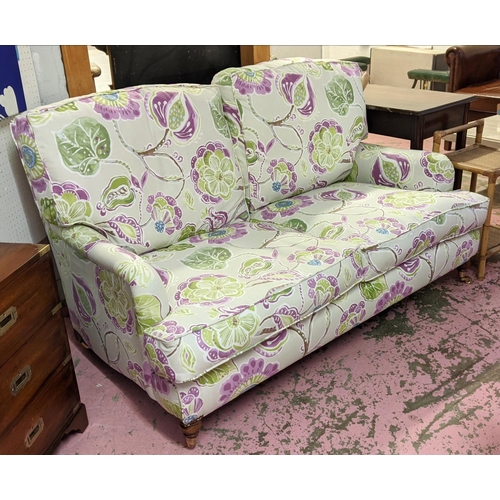 216 - HOWARD STYLE SOFA, two seater, with vibrant botanical print upholstery, turned front supports and ca... 