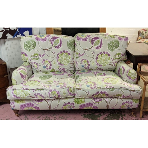 216 - HOWARD STYLE SOFA, two seater, with vibrant botanical print upholstery, turned front supports and ca... 