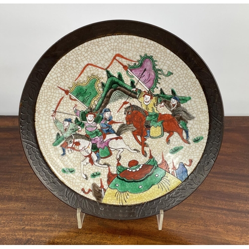 16 - CHINESE STONEWARE PLATE, decorated with battle scene in bright enamels, 33cm diam.