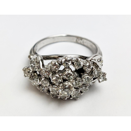 31 - A WHITE METAL AND DIAMOND CLUSTER RING, the centre with a flower head setting surrounded by C scroll... 