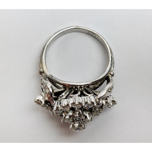 31 - A WHITE METAL AND DIAMOND CLUSTER RING, the centre with a flower head setting surrounded by C scroll... 