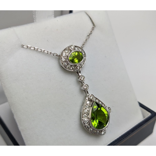 40 - AN 18CT WHITE GOLD PERIDOT AND DIAMOND SET PENDANT NECKLACE, the pear shaped drop pendant surrounded... 