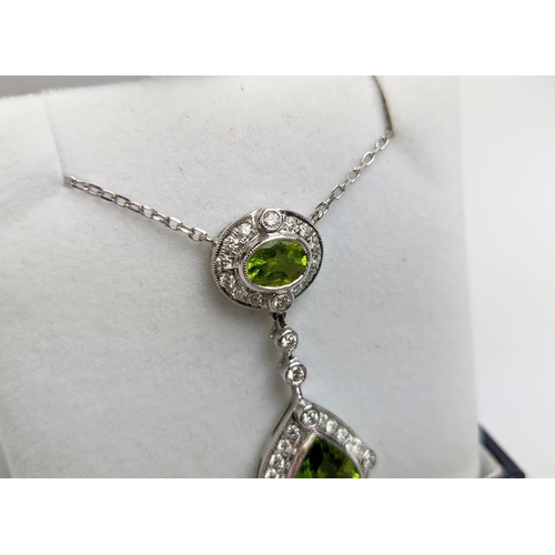 40 - AN 18CT WHITE GOLD PERIDOT AND DIAMOND SET PENDANT NECKLACE, the pear shaped drop pendant surrounded... 