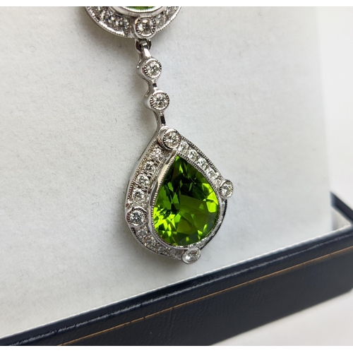 40 - AN 18CT WHITE GOLD PERIDOT AND DIAMOND SET PENDANT NECKLACE, the pear shaped drop pendant surrounded... 