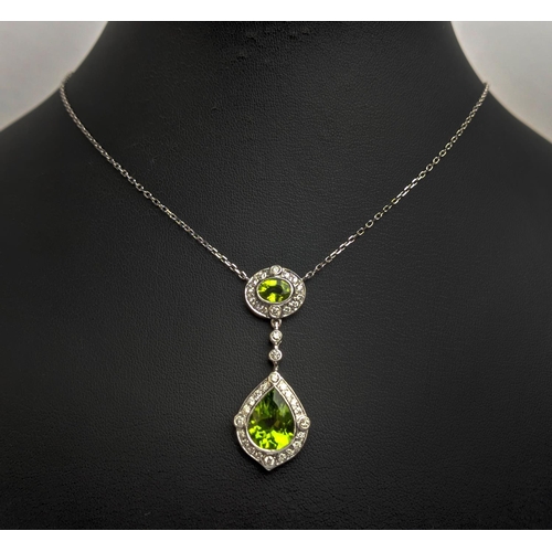 40 - AN 18CT WHITE GOLD PERIDOT AND DIAMOND SET PENDANT NECKLACE, the pear shaped drop pendant surrounded... 