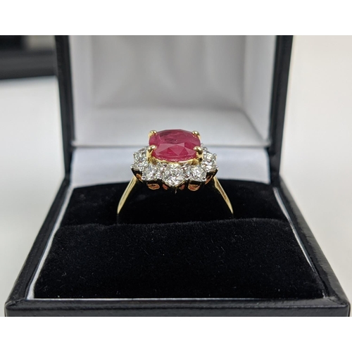 42 - AN 18CT GOLD RUBY AND DIAMOND CLUSTER RING, the mixed cut ruby of 4.11 carats, surrounded by ten rou... 