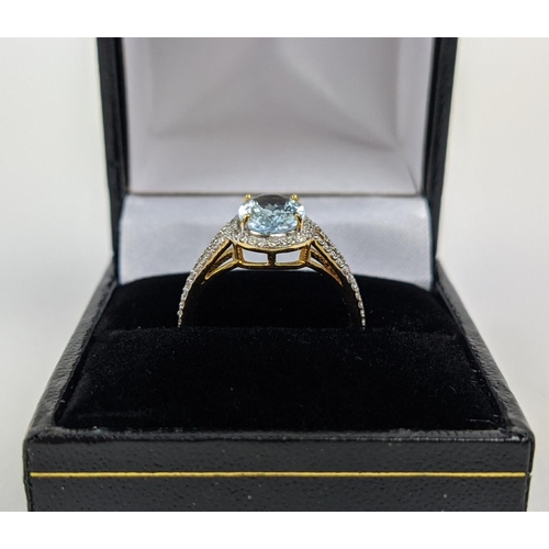 50 - A 14CT GOLD AQUAMARINE AND DIAMOND SET DRESS RING, the mixed cut aquamarine stone surrounded by halo... 