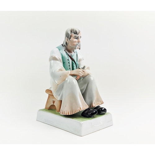 22 - A ZSOLNAY FIGURE OF A MAN WITH A KNIFE, seated, made in Hungary, hand painted, 33cm high