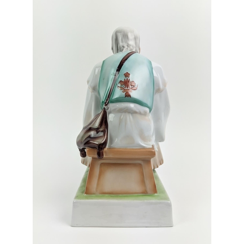 22 - A ZSOLNAY FIGURE OF A MAN WITH A KNIFE, seated, made in Hungary, hand painted, 33cm high