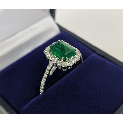 36 - AN 18CT WHITE GOLD EMERALD AND DIAMOND SET DRESS RING, the central step-cut emerald of approximately... 