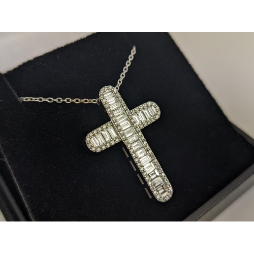 37 - A 18CT WHITE GOLD DIAMOND SET CROSS PENDANT, set with baguette cut diamonds and a border of round br... 