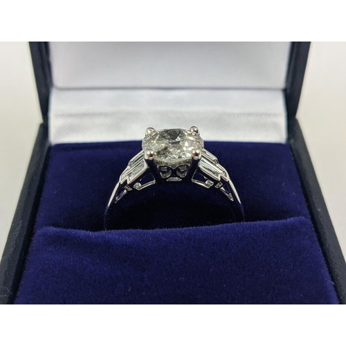 42 - AN 18CT WHITE GOLD DIAMOND SOLITAIRE RING, with baguette cut diamonds to shoulders, the central roun... 