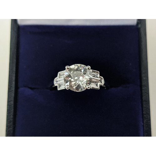 42 - AN 18CT WHITE GOLD DIAMOND SOLITAIRE RING, with baguette cut diamonds to shoulders, the central roun... 