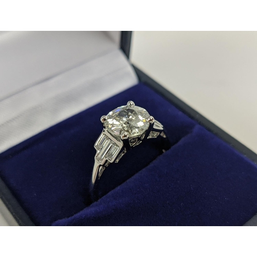 42 - AN 18CT WHITE GOLD DIAMOND SOLITAIRE RING, with baguette cut diamonds to shoulders, the central roun... 